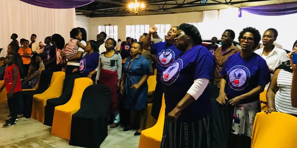A group of people engaged in a lively indoor gathering, some wearing matching blue shirts.