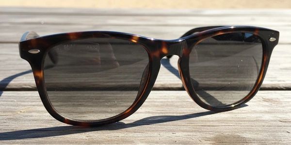 Tortoiseshell sunglasses resting on a wooden surface in sunlight.