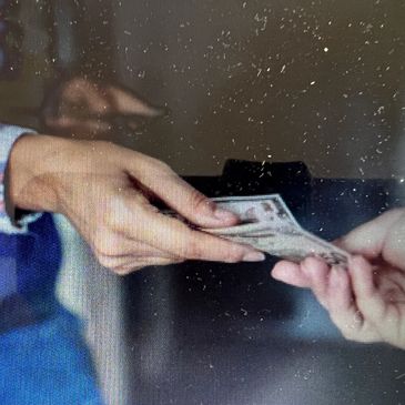 Hands exchanging cash in a financial transaction.