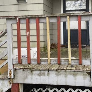 Wooden porch railing with mismatched vertical slats in different colors.