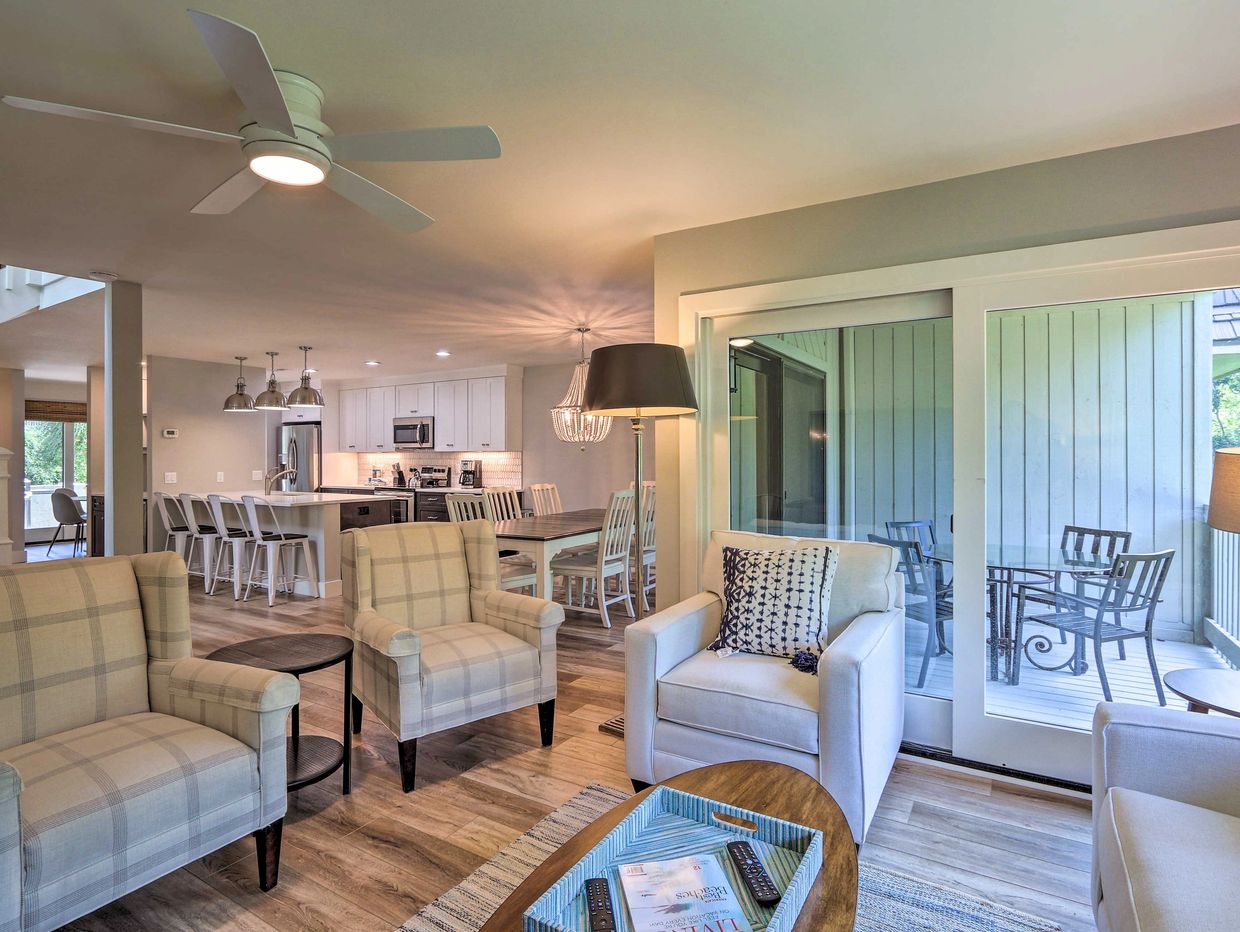 Cozy living room with plaid and white armchairs, leading to a dining area and kitchen.