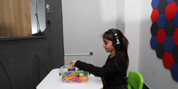 Kulaklık takan çocuk oyuncak bloklarla oynuyor.