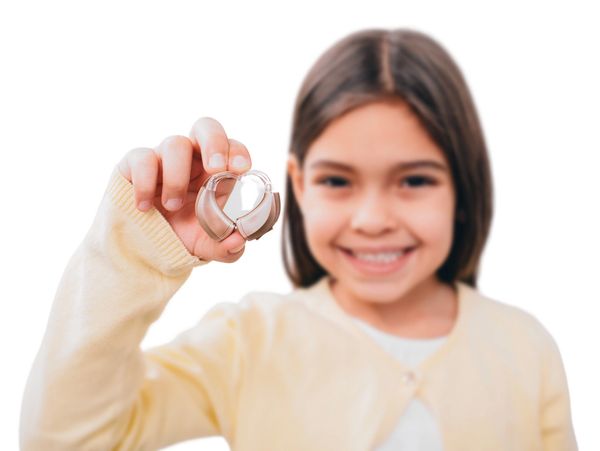 çocuğun elinde işitme cihazı tuttuğu ve çocuklara özel işitme cihazı fotoğrafı