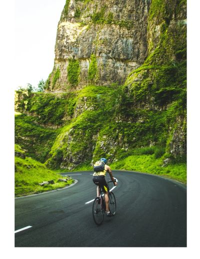 Un cycliste monte une route de montagne en lacets.