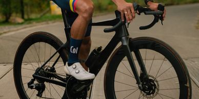 Cyclist pedaling a black road bike on a paved path.