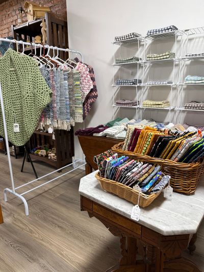 Handmade knitwear and colorful folded fabrics displayed in a cozy shop.