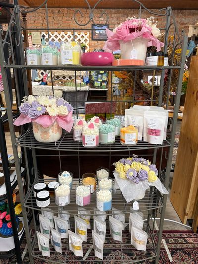 Display of colorful floral and scented products on a metal shelf in a shop.