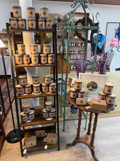 Display of scented candles on shelves and a small table in a store.