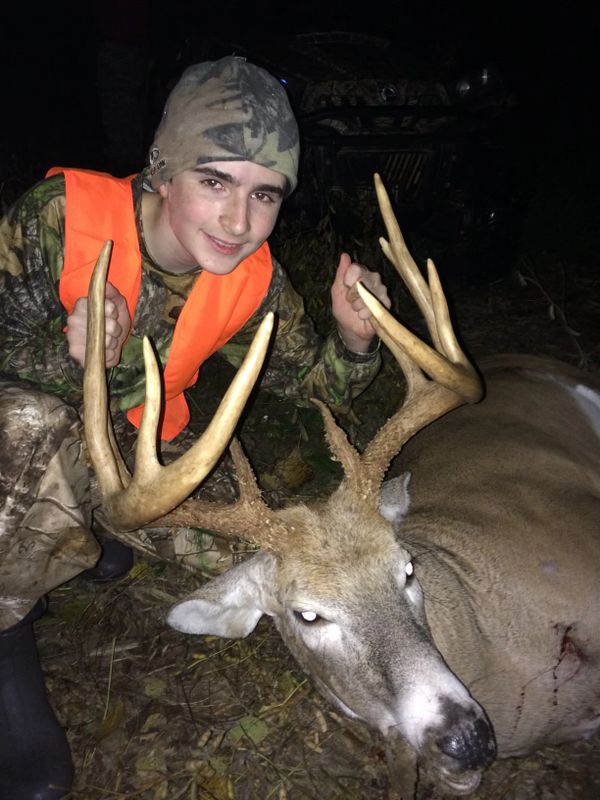 Young hunter posing with a large buck at night.Hunting, trophy whitetails, buck hunting, big buck, whitetail hunts.