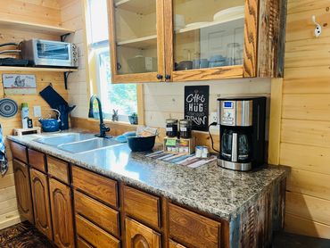 Cabin kitchen with sink, countertop, cabinets, microwave, and coffee station.