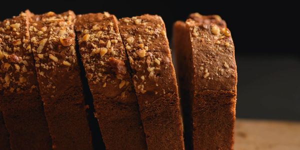 Sliced nut-topped brown loaf on a wooden board.