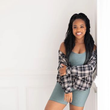 Smiling woman in casual outfit leaning against wall.