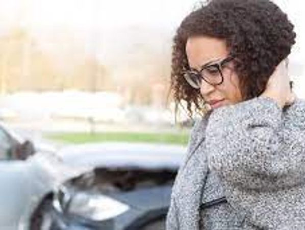 Person holding neck in pain in front of car accident.