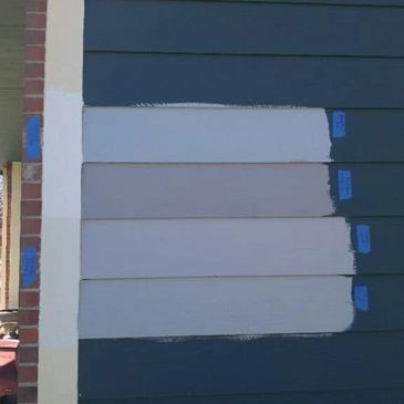 House siding paint color samples on dark blue wall.