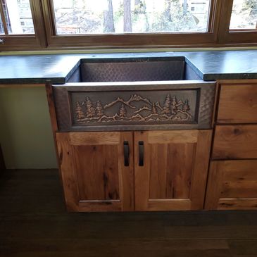 Rustic copper kitchen sink with mountain design.