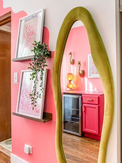 Colorful hallway with a green-framed mirror and pink-themed decor.