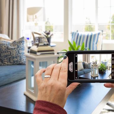 A woman taking a photo of a beautiful room after home staging using a phone.