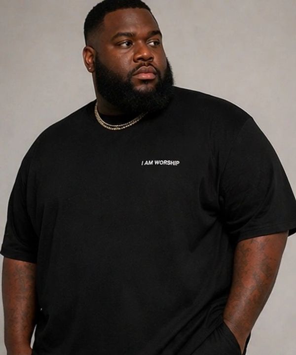 A man wearing a black t-shirt with the words 'I AM WORSHIP' looking away.
