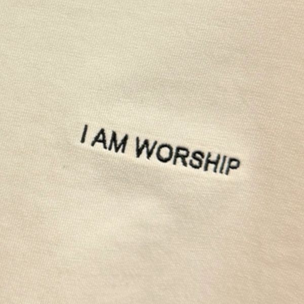 Close-up of fabric with 'I AM WORSHIP' embroidered in black.