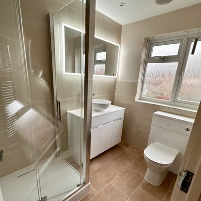 Modern bathroom with a glass shower, white vanity, and toilet.