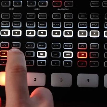Fingers adjusting buttons on a professional audio or video mixer panel.