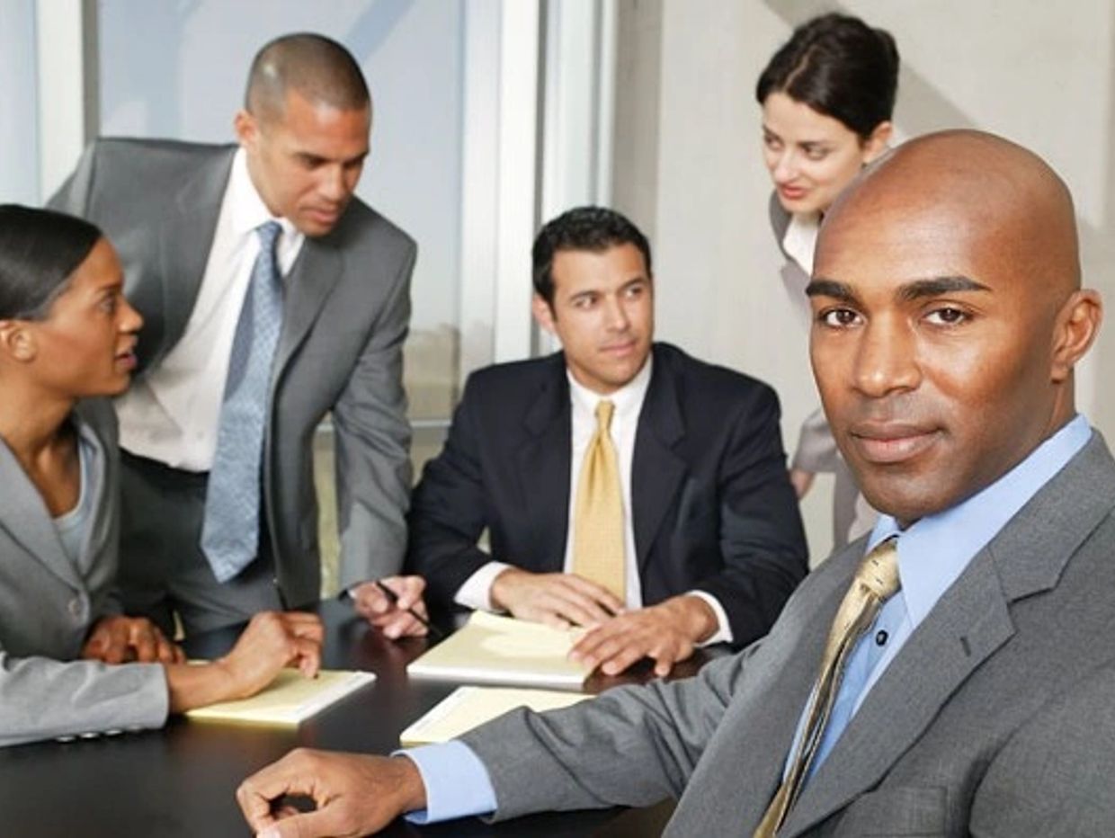 A confident businessman in a suit leading a meeting with colleagues.