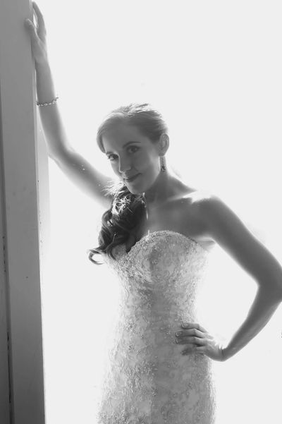 Bride in a lace wedding dress posing by a window.