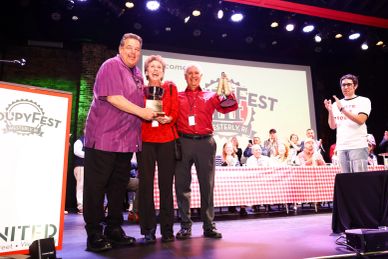 Winners celebrating with trophies on stage at a festival.
