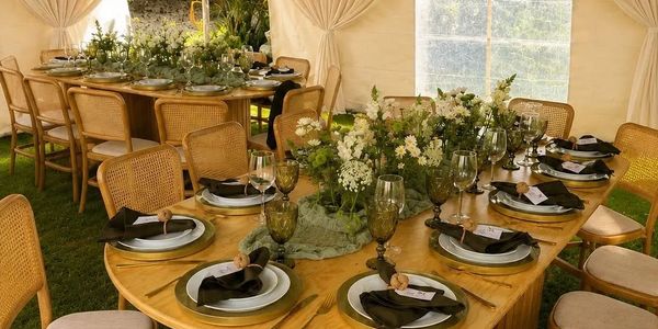 Mesa decorada elegantemente para evento con flores y vajilla.