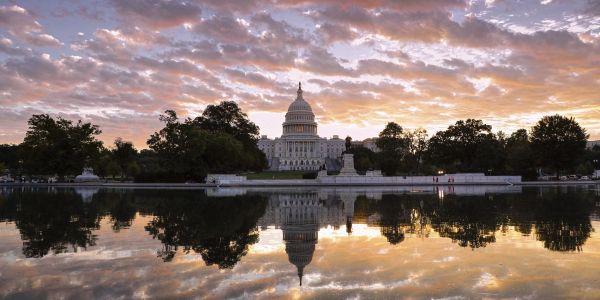 Sunset over the U.S. Capitol with reflections in water.
