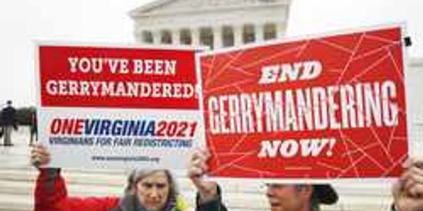 Protesters hold signs demanding an end to gerrymandering in front of a government building.