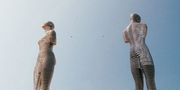 An image of a modern, metal statue of a woman and a man facing away from each other. 