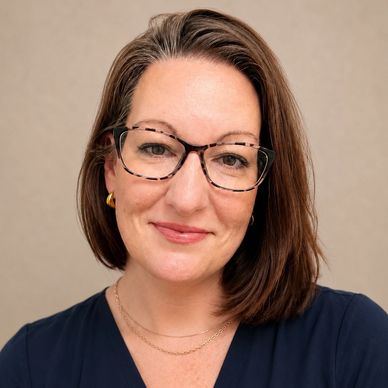 Smiling woman wearing glasses and a navy blue top.