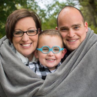 Happy family wrapped in a blanket outdoors.