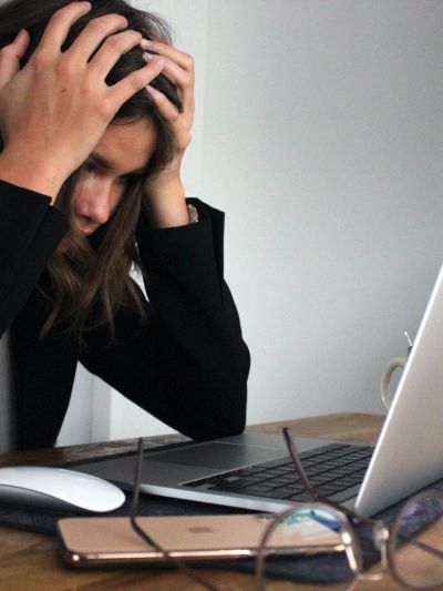 Stressed woman holding her head while working on a laptop.