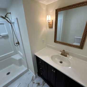 Brass accent bathroom with marble floor and dark vanity 