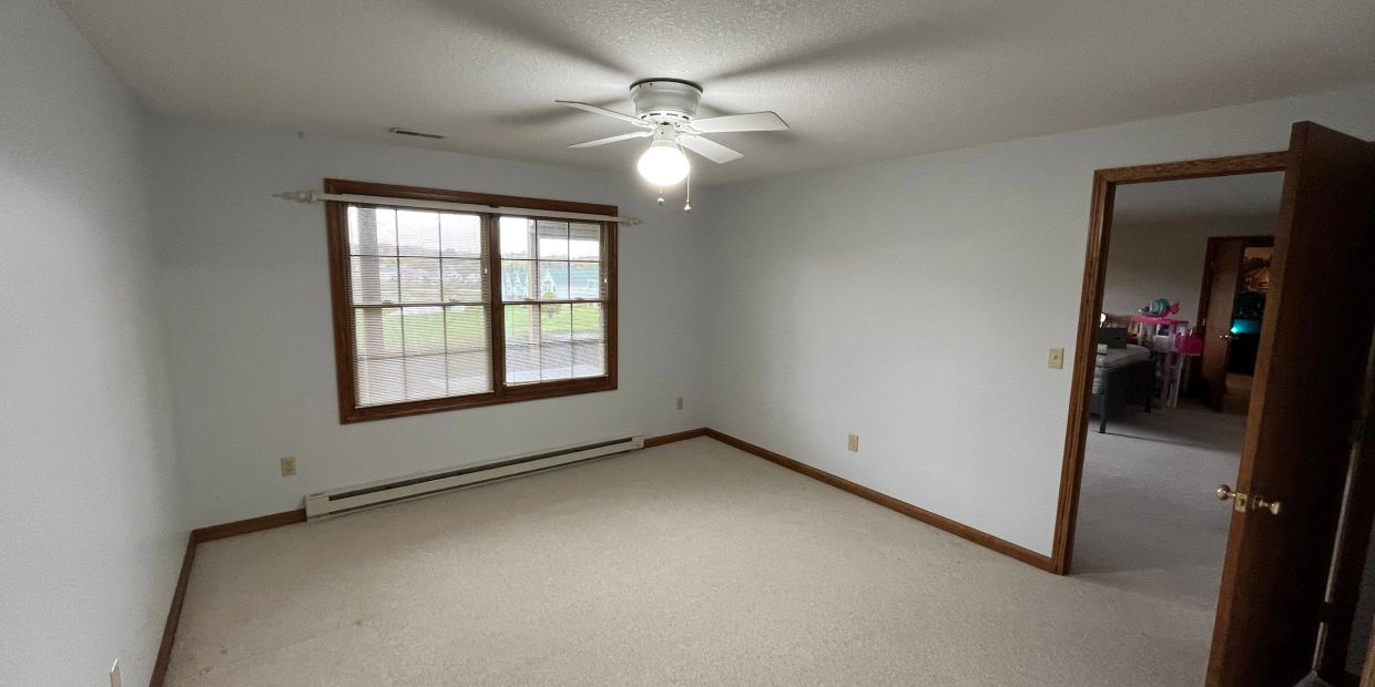 Empty room with beige carpet, white walls, and a ceiling fan.