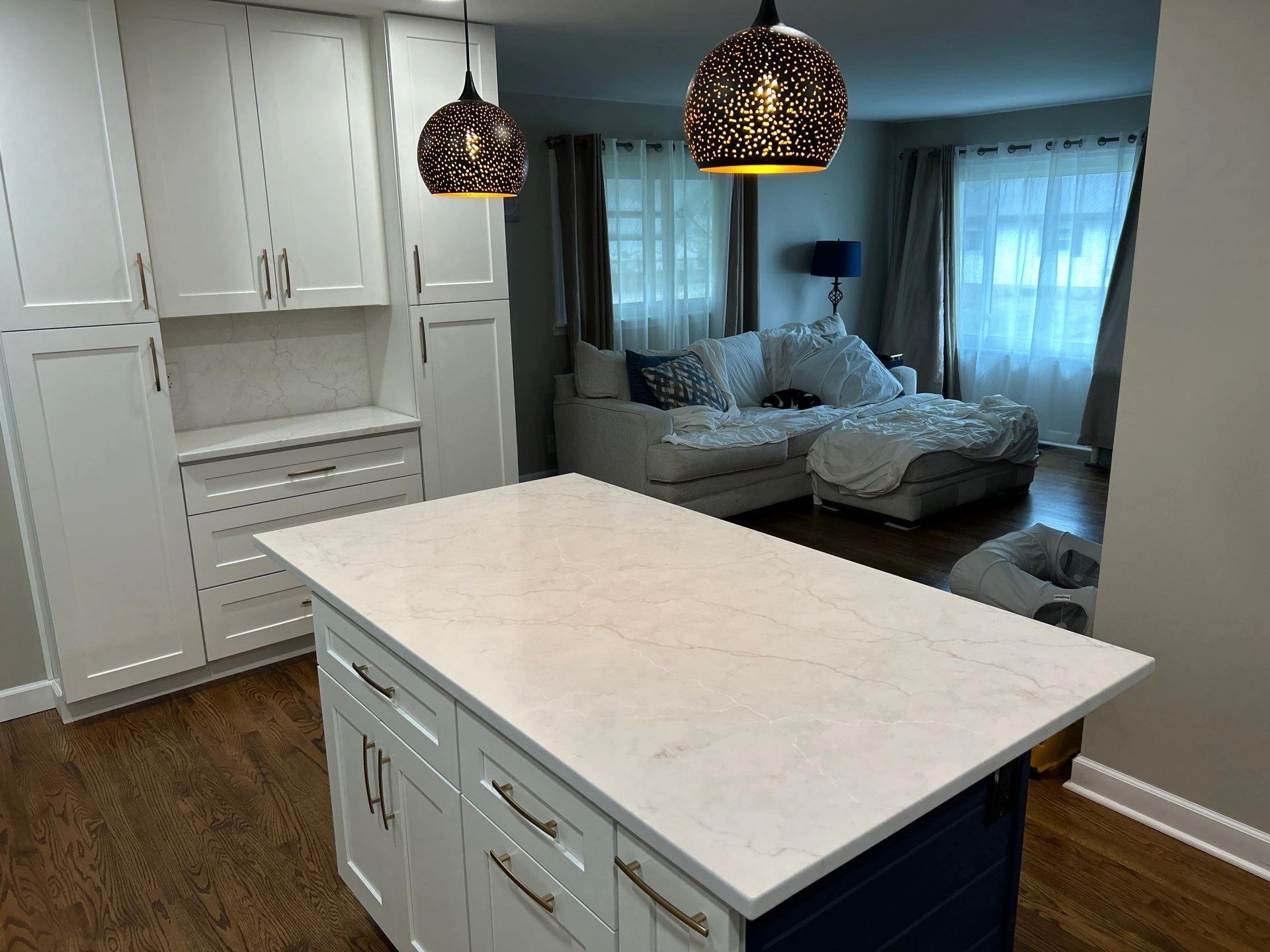 Modern kitchen island with white cabinets and decorative hanging lamps.