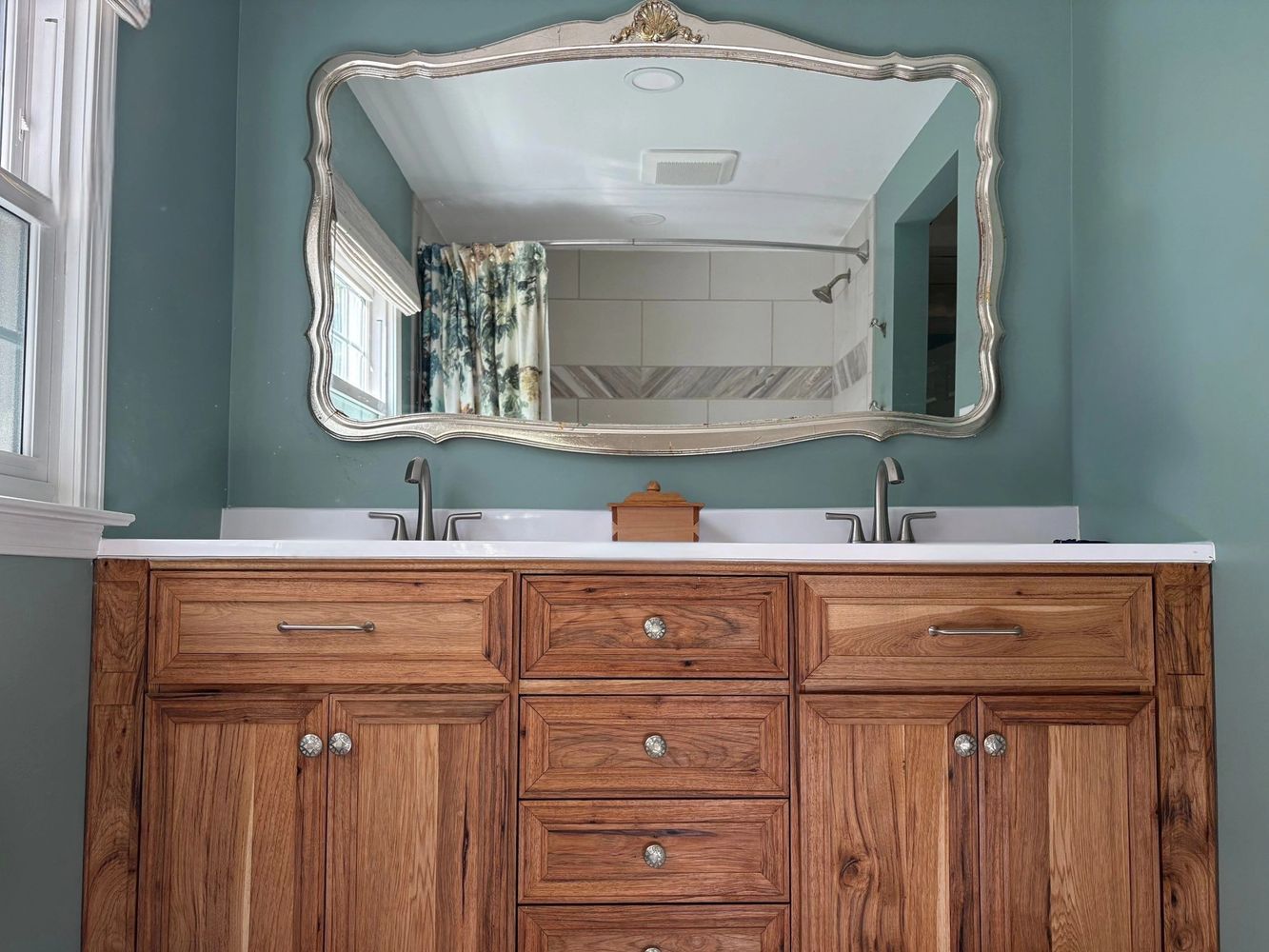 Warm wood and sage green bathroom vanity with white counter