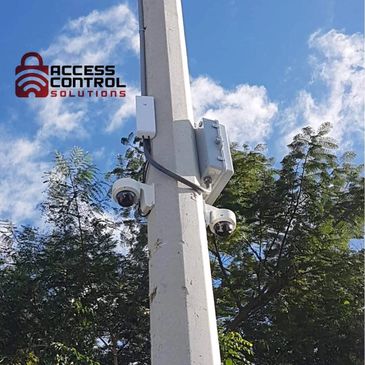 Security cameras mounted on a pole with Access Control Solutions logo.