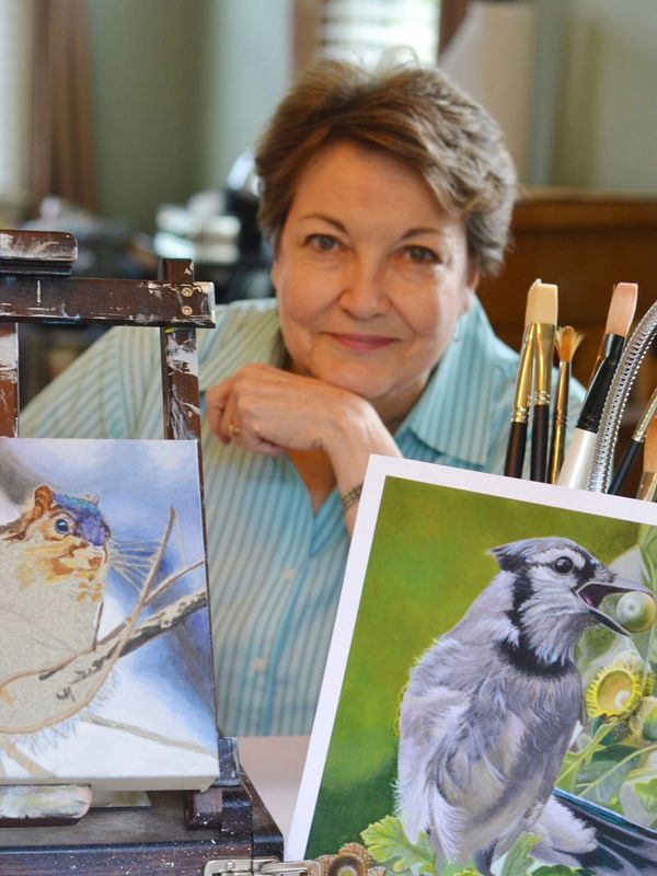 Artist with art and brushes displayed.