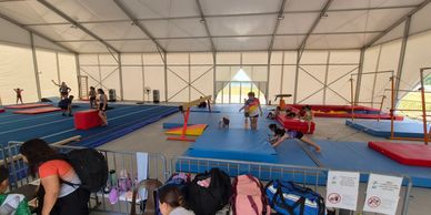 Gymnastics training session inside a large tent with children practicing.