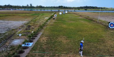Archers aiming at targets on a grassy field during daytime.