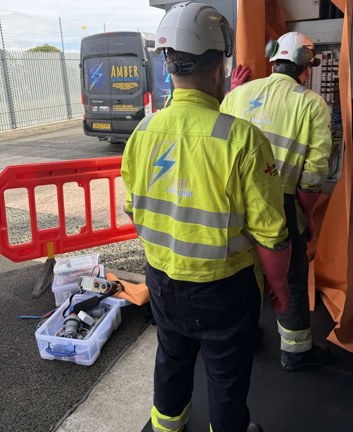 Electricians in yellow jackets working with equipment.