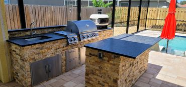 Parallel shape outdoor kitchen that has a grill, side burner, sink, drawers, and access doors.