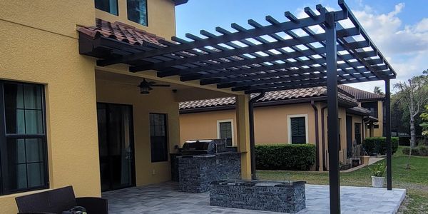 Custom built alluminum pergola in bronze over a firetable with granite and natural stone sides