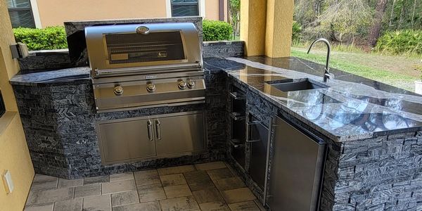 L Shape custom outdoor kitchen in Land O' Lakes Tampa featuring a Firemagic grill with Magic Window
