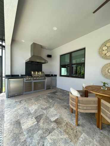 Linear outdoor kitchen with exhaust hood, fridge, access doors, side burner, sink, and ice maker.