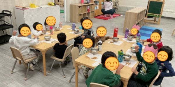 Children sitting around a table enjoying a meal in a classroom.