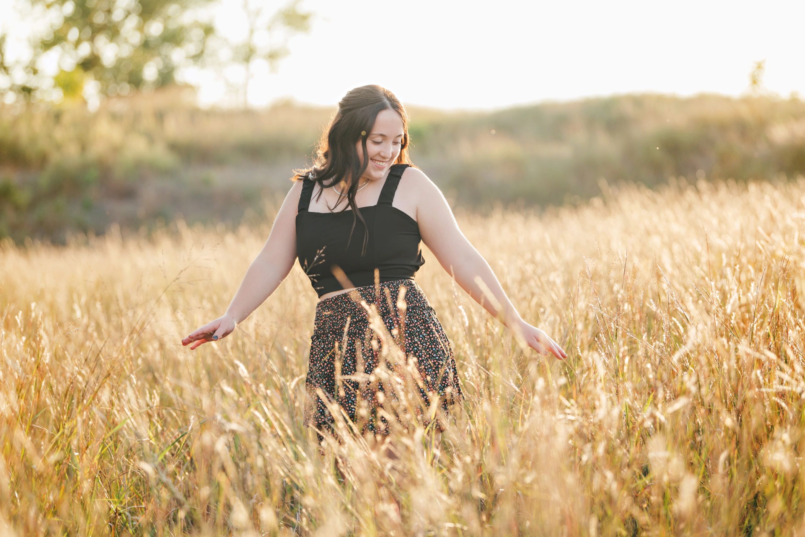 High school senior girl dancing in tall grasses